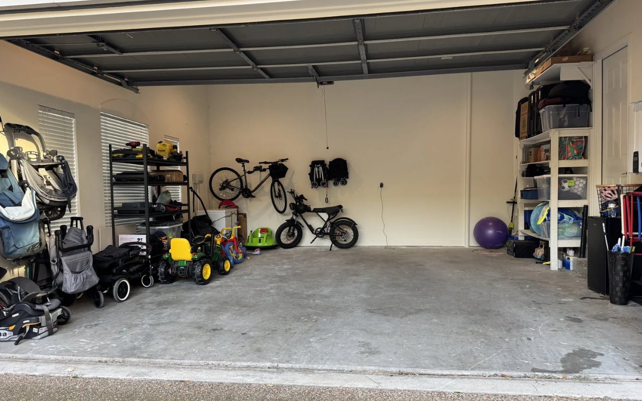 Two-car garage organized with shelving, wall-mounted bikes, and kids' ride-on toys